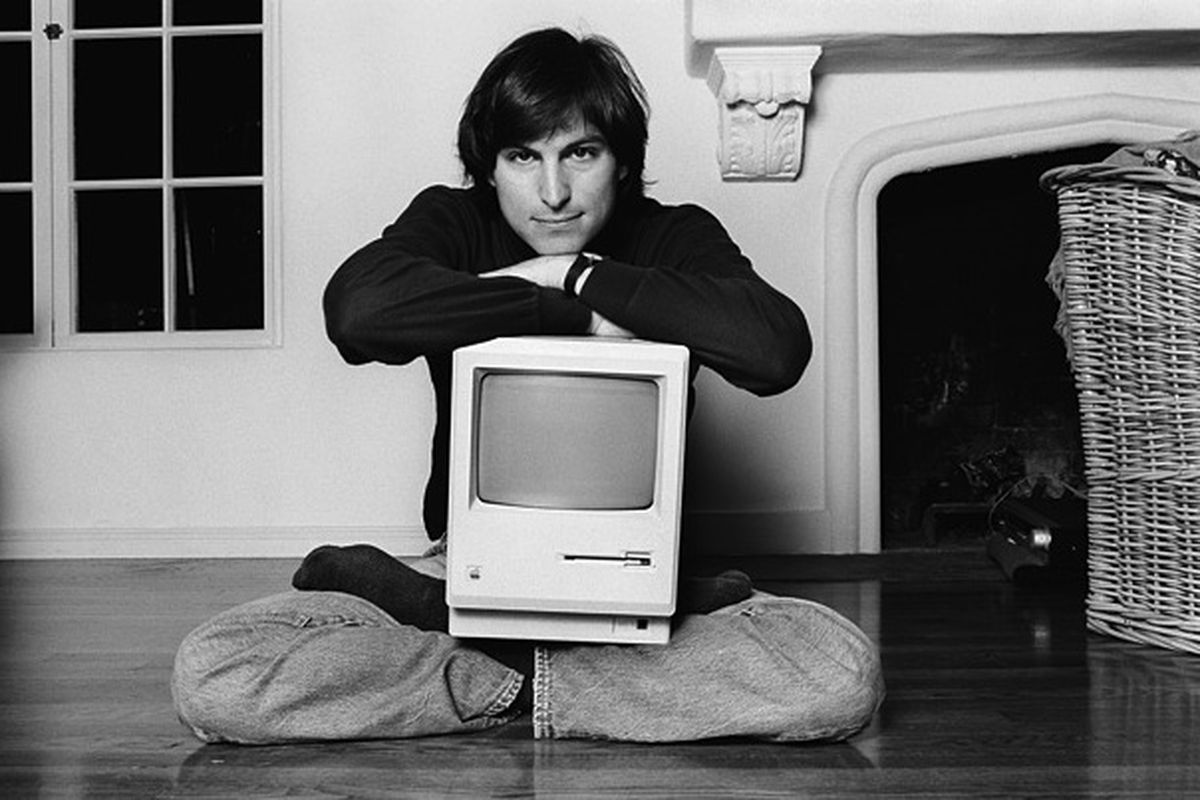 Steve Jobs sitting on the floor with an iMac